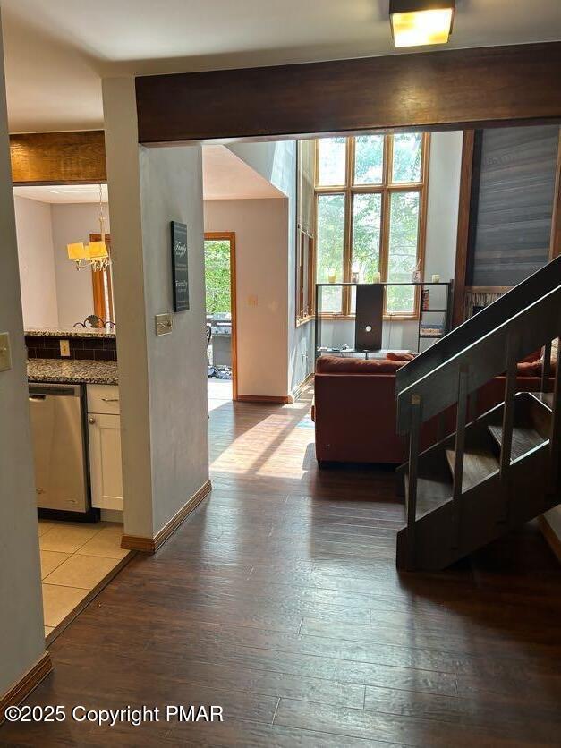 living area featuring beamed ceiling, stairs, light wood-type flooring, and baseboards