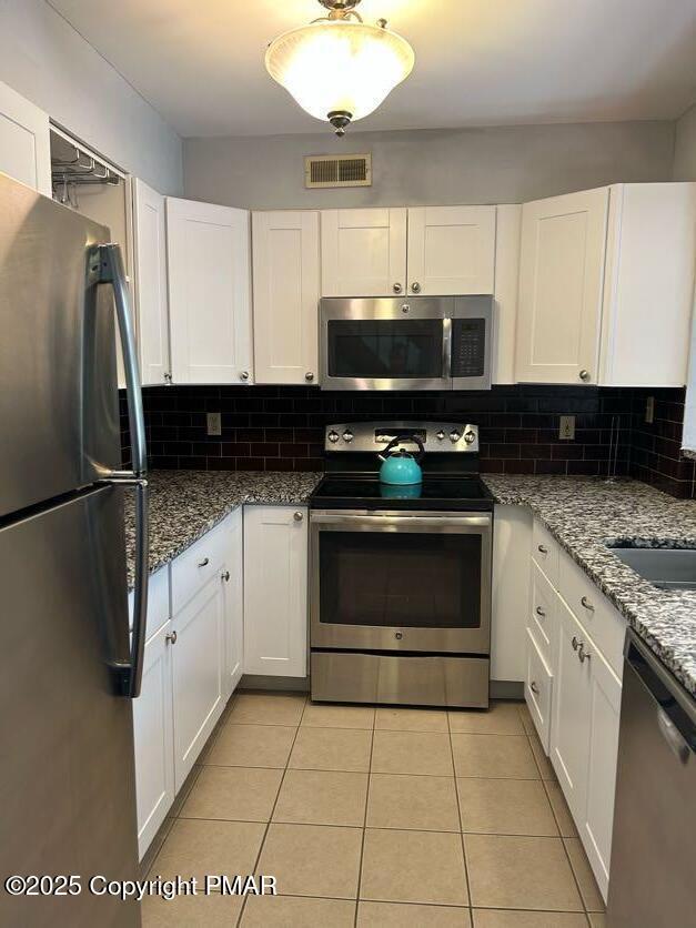 kitchen with white cabinetry, backsplash, visible vents, and appliances with stainless steel finishes