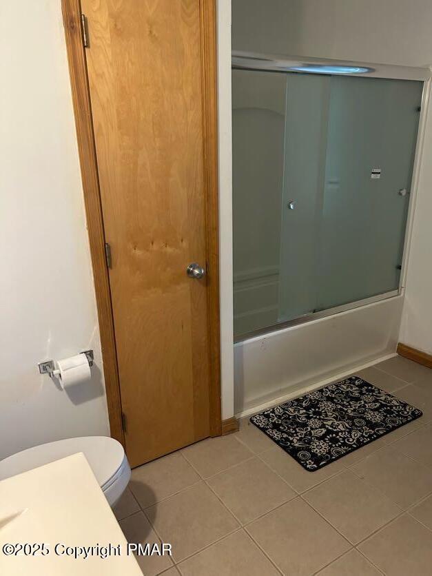 bathroom with tile patterned flooring, enclosed tub / shower combo, and toilet