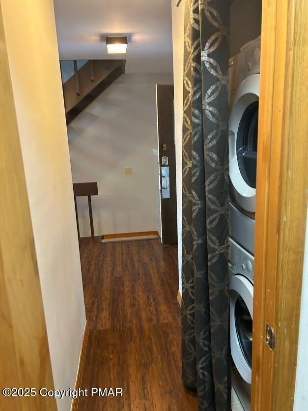 washroom with dark hardwood / wood-style flooring and stacked washer / drying machine