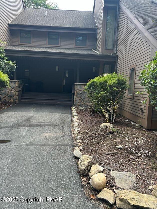 view of front facade featuring aphalt driveway, covered porch, and a garage