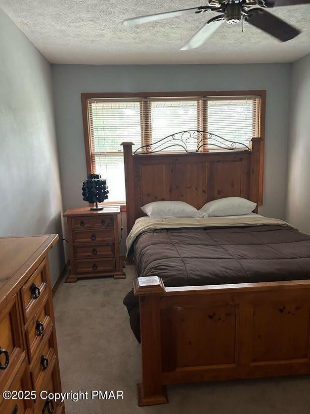 carpeted bedroom with ceiling fan and a textured ceiling