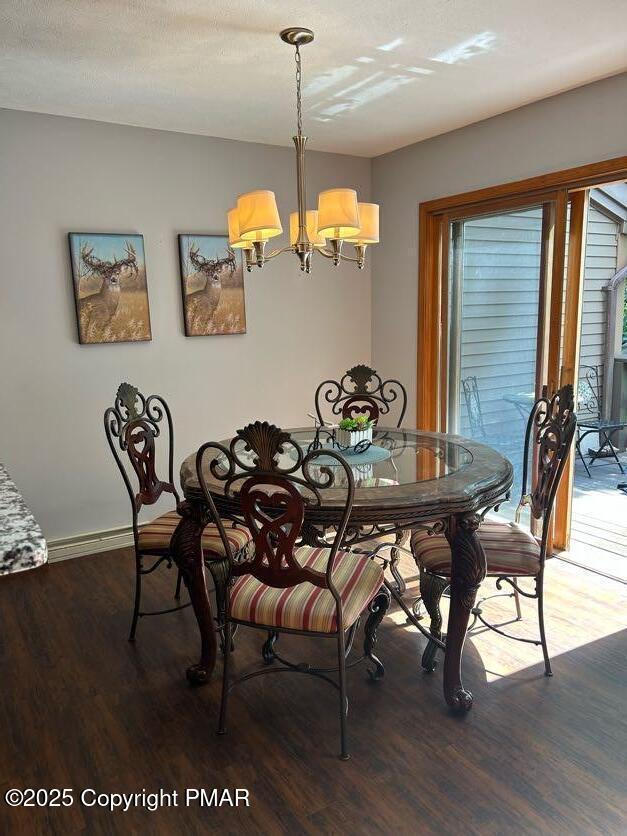 dining room featuring a chandelier, baseboards, and wood finished floors