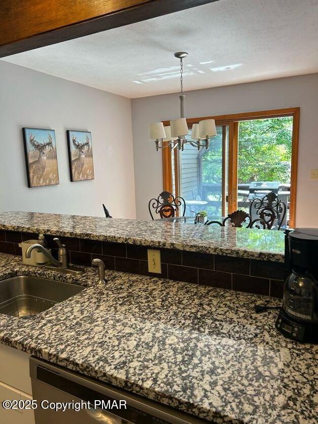 kitchen featuring sink, pendant lighting, a chandelier, and dark stone counters