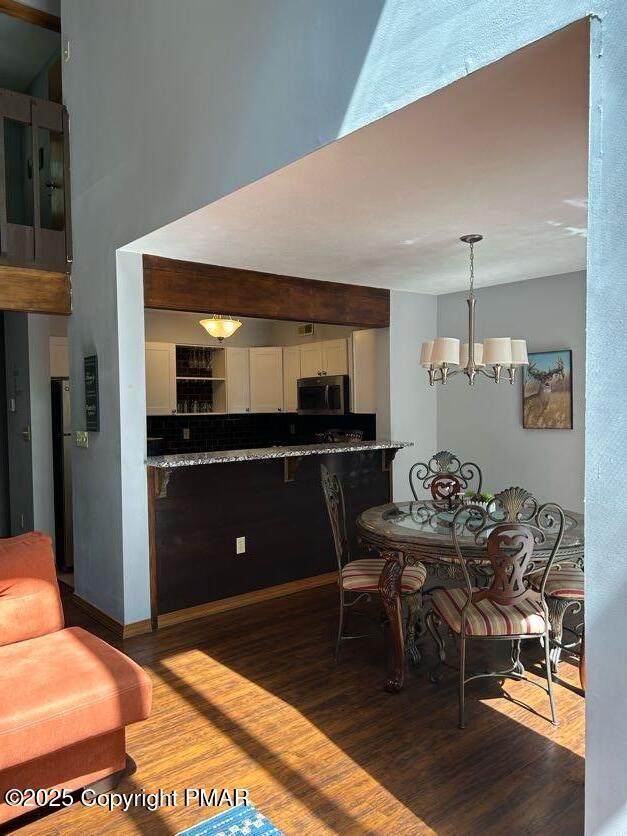 dining area with hardwood / wood-style floors and a chandelier