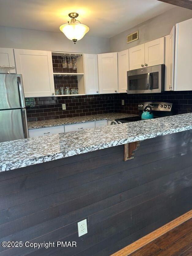 kitchen with white cabinetry, tasteful backsplash, visible vents, and appliances with stainless steel finishes