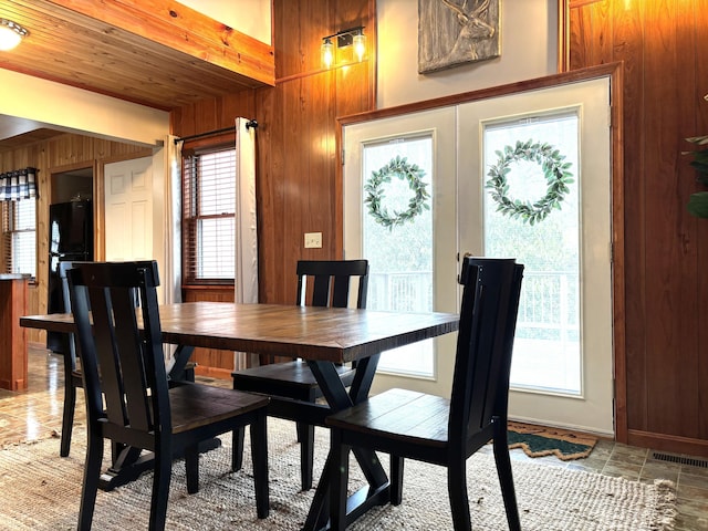 dining room featuring wooden walls, baseboards, and visible vents
