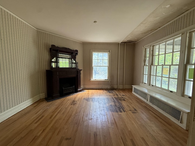 712 Thomas St, Stroudsburg, PA 18360 - unfurnished living room featuring wood finished floors, a fireplace, wallpapered walls, radiator heating unit, and baseboards