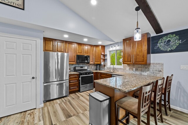 19 Conservancy Ct, Gouldsboro, PA 18424 - kitchen featuring stainless steel appliances, a sink, brown cabinetry, a peninsula, and lofted ceiling