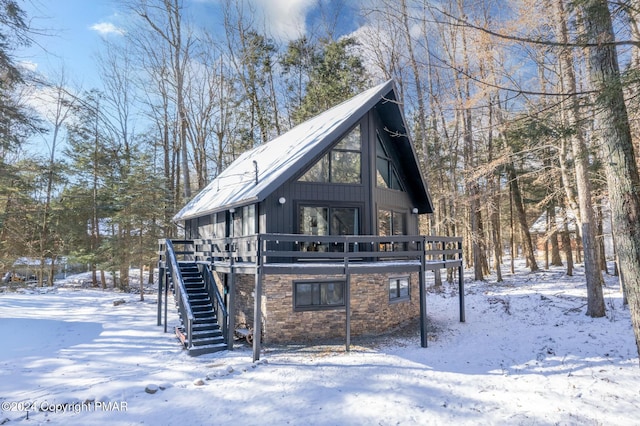 view of front of home featuring stairs, stone siding, and a wooden deck