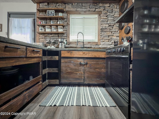 bar featuring black appliances, wood finished floors, a sink, and under cabinet range hood