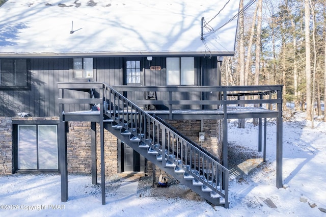 snow covered property featuring stairs and stone siding