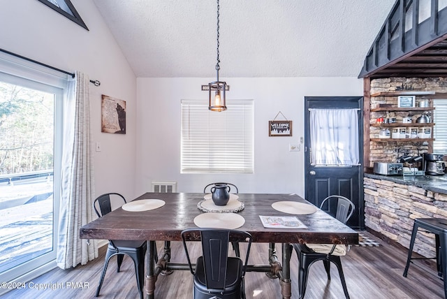 dining area with lofted ceiling, a textured ceiling, visible vents, and wood finished floors