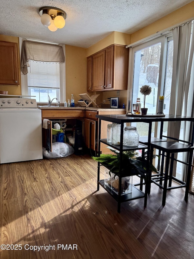 kitchen with washer / clothes dryer, wood-type flooring, and a textured ceiling