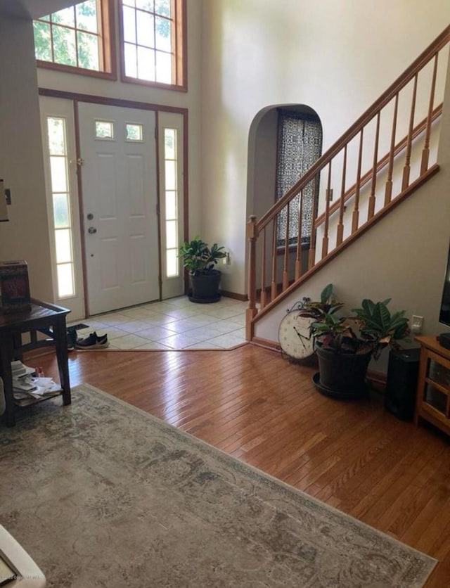 foyer entrance with arched walkways, plenty of natural light, a high ceiling, and hardwood / wood-style floors