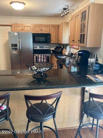 kitchen with glass insert cabinets, ornamental molding, a kitchen breakfast bar, wood finished floors, and stainless steel appliances