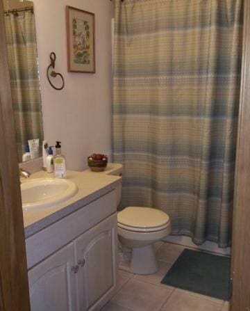 bathroom featuring a shower with curtain, toilet, vanity, and tile patterned flooring