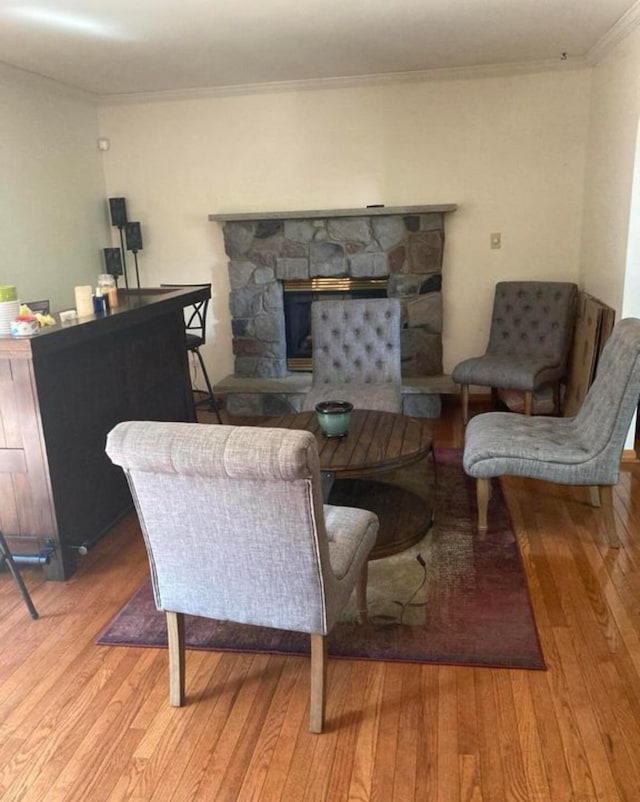 living room featuring wood finished floors, a fireplace, and ornamental molding