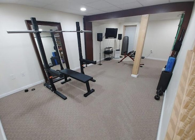 workout area featuring baseboards and a paneled ceiling