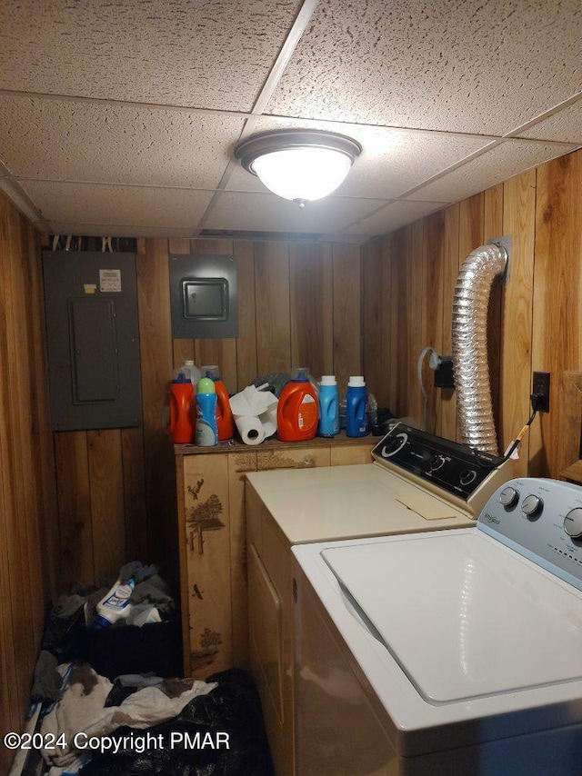 laundry room with washer and dryer, electric panel, wood walls, and laundry area