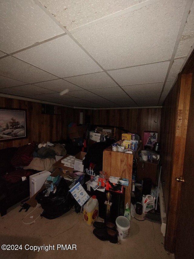 finished basement with a drop ceiling and wood walls