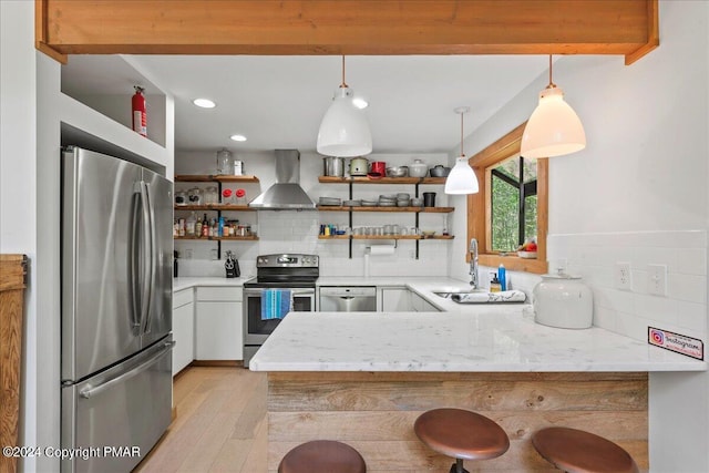 kitchen featuring stainless steel appliances, a peninsula, wall chimney range hood, decorative backsplash, and open shelves