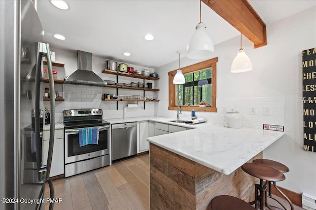 kitchen with stainless steel appliances, a peninsula, wall chimney range hood, open shelves, and beamed ceiling