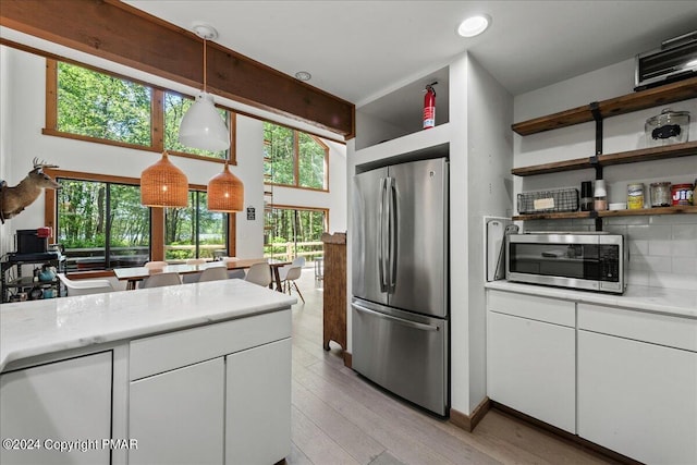 kitchen featuring stainless steel appliances, white cabinets, light countertops, and light wood finished floors