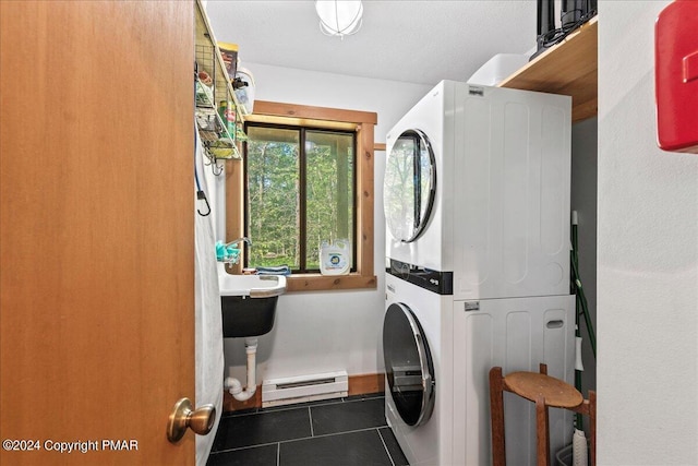 laundry area featuring stacked washing maching and dryer, laundry area, baseboard heating, and tile patterned floors