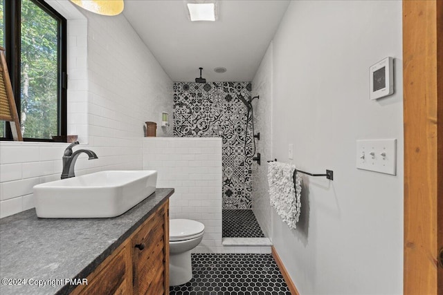 bathroom with a wealth of natural light, tiled shower, vanity, and toilet