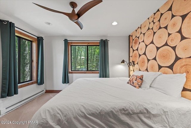 bedroom featuring a baseboard radiator, multiple windows, a ceiling fan, and carpet flooring