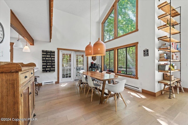 dining area with a baseboard heating unit, a towering ceiling, french doors, light wood-type flooring, and beamed ceiling