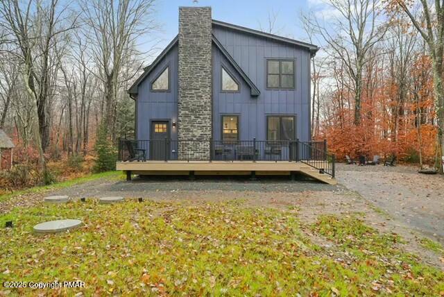 back of property with a chimney, a deck, and board and batten siding