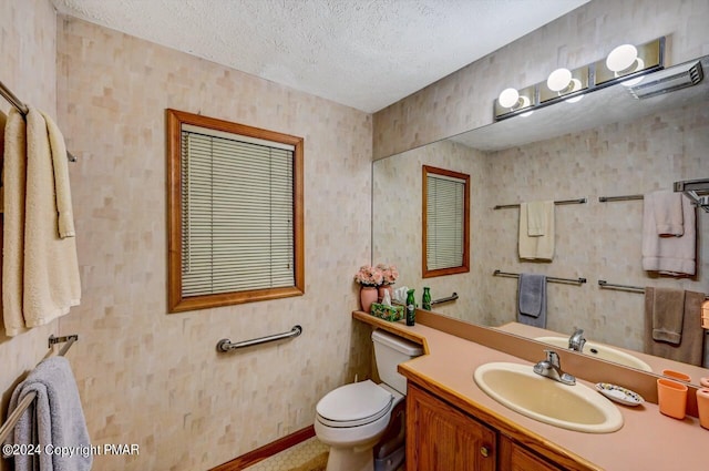 bathroom featuring baseboards, a textured ceiling, vanity, and toilet