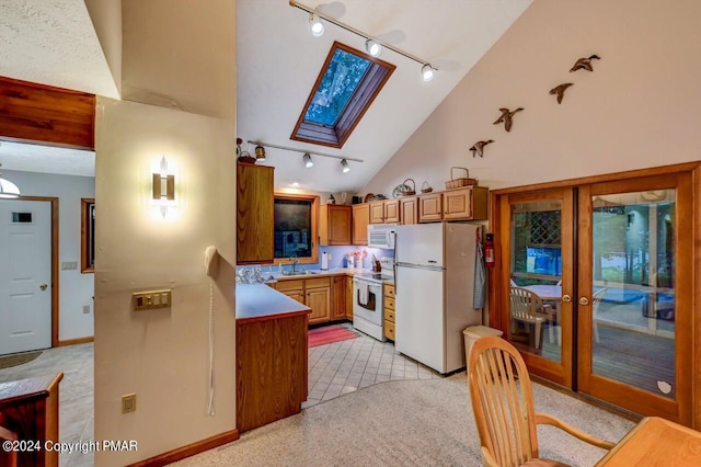 kitchen featuring brown cabinets, french doors, a skylight, white appliances, and a sink