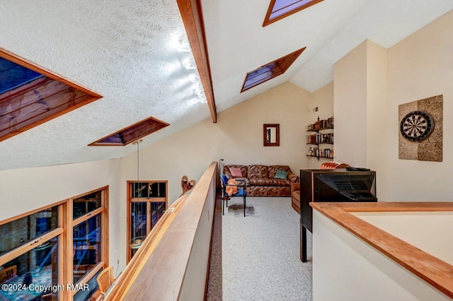 hallway featuring vaulted ceiling with skylight, a textured ceiling, and carpet