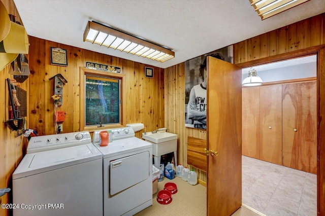 clothes washing area featuring washer and clothes dryer, laundry area, and wood walls