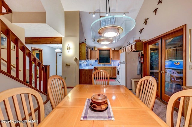 dining space featuring french doors, an inviting chandelier, a towering ceiling, and track lighting