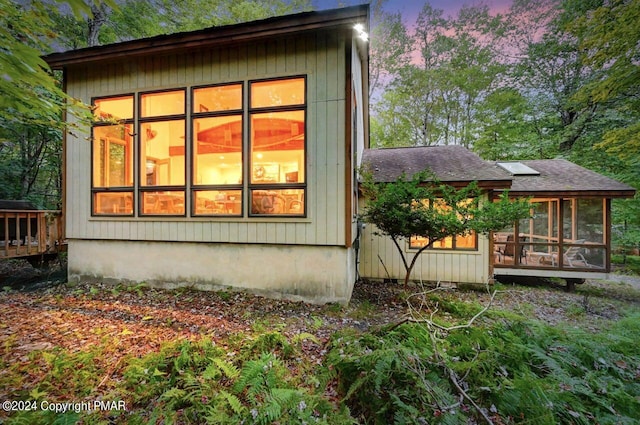 view of side of home with roof with shingles and a sunroom