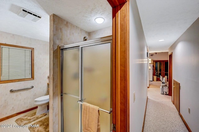 full bathroom featuring baseboards, a shower stall, a textured ceiling, and toilet