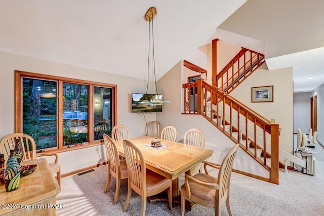 dining space featuring stairway, visible vents, carpet flooring, and vaulted ceiling