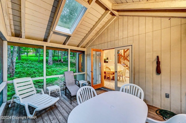 sunroom with vaulted ceiling with skylight and a healthy amount of sunlight