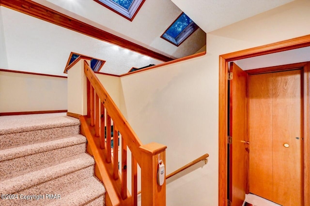 staircase featuring lofted ceiling with skylight, baseboards, and wood finished floors