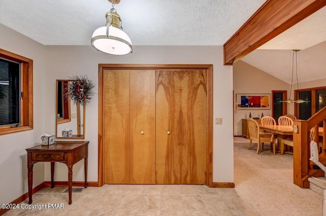 entrance foyer with visible vents, a textured ceiling, lofted ceiling with beams, and baseboards