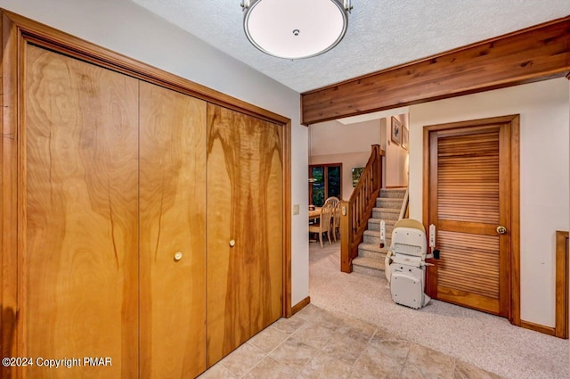 bedroom with light carpet, a textured ceiling, and baseboards