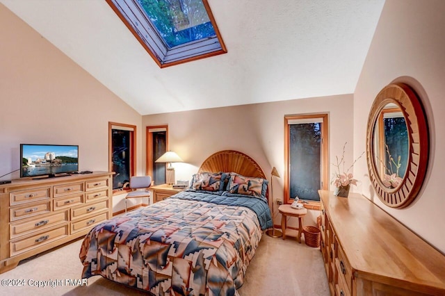 bedroom with vaulted ceiling with skylight and light colored carpet