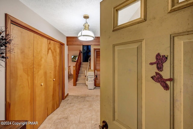 corridor with stairway and a textured ceiling