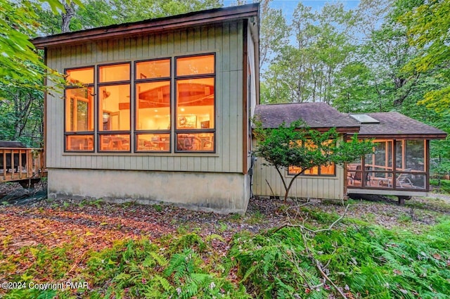 view of side of home featuring roof with shingles and a sunroom