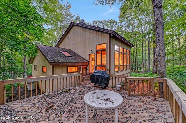 wooden deck with area for grilling and a sunroom