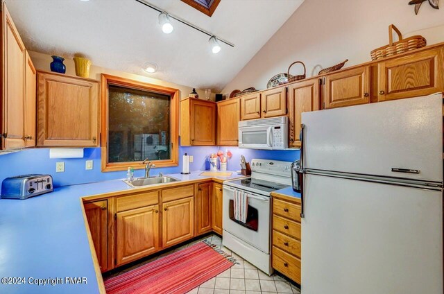 kitchen with a sink, white appliances, light countertops, light tile patterned floors, and vaulted ceiling